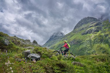 nice active senior woman riding her electric mountain bike in the Jamtal Valley, silvretta mountain range near Gaschurn, Tyrol, Austria