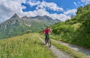nice active senior woman riding her electric mountain bike in the silvretta mountain range near Gaschurn, Tyrol, Austria