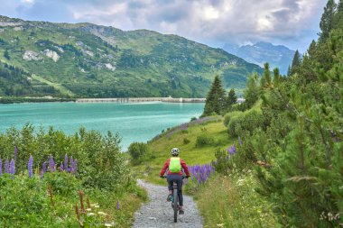 nice active senior woman riding her electric mountain bike in the silvretta mountain range above barrier lake Kopssee,near Gaschurn, Tyrol, Austria