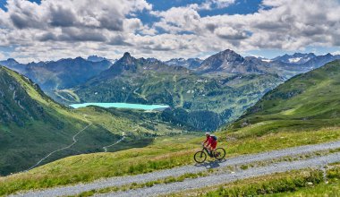 nice active senior woman riding her electric mountain bike in the silvretta mountain range above barrier lake Kopssee,near Gaschurn, Tyrol, Austria