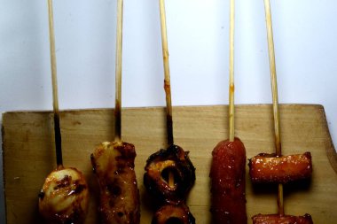 Endonezya sokak atıştırmalıkları, sosis, köfte, mantar, nugget vs. gibi beyaz arka planda izole edilmiş şeylerden oluşan çeşitli ızgara çeşitleri.