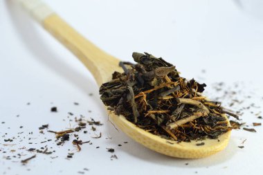 Beyaz arka planda bambu kaşığında çay.