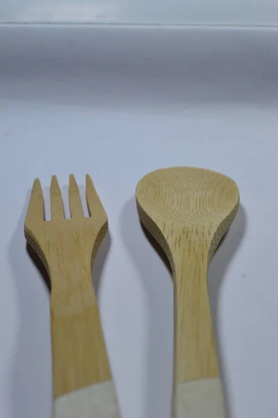 Saf beyaz arka planda bambudan yapılmış bir çatal bıçak seti.