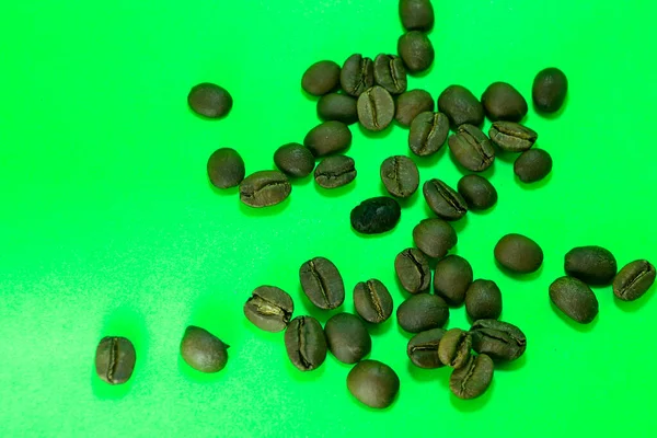 Verspreide Koffiebonen Met Groene Achtergrond — Stockfoto