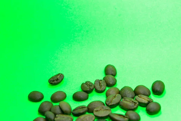 Verspreide Koffiebonen Met Groene Achtergrond — Stockfoto