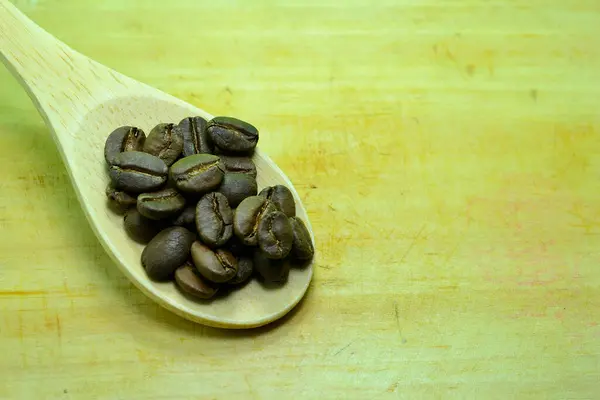 Bambu kaşığında kahve çekirdekleri güzel ahşap bir arka planda..
