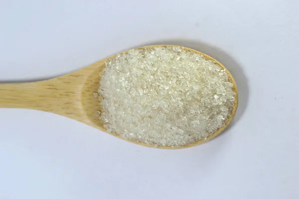 Bir kaşık dolusu şeker. Şeker bambu kaşığının içinde. Beyaz arkaplan bulanık fotoğraf