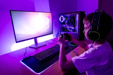 Oyuncu, oyun bilgisayarında joypad ile oyun oynuyor. Su soğutma kutusu, joypad, fare, kulaklık ile modern oyun düzeneği.