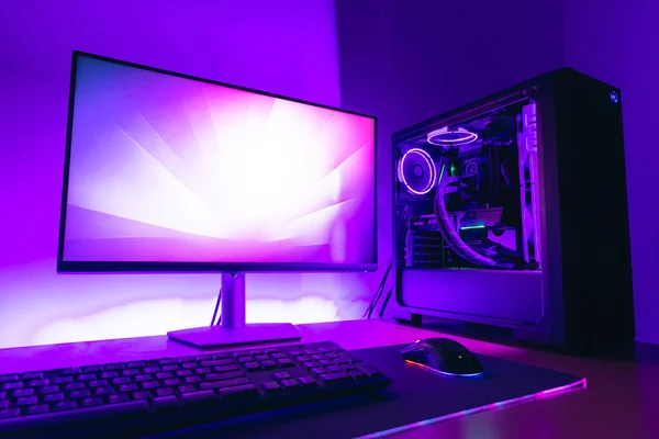 ディスプレイ 水冷ケース キーボード ゲームマット上のマウスと現代のゲームコンピュータのセットアップ 背景に紫色のLedライト — ストック写真
