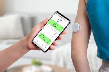 Mobil uygulama ve sensör yardımıyla kan şekeri ölçümü. El, telefonu çocuğun el konseptinde bulunan sensöre yaklaştırır. 