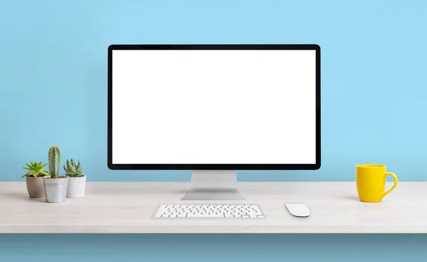 带有白色隔离屏幕的计算机显示 可在工作台上显示 用咖啡杯和植物清洁成分 背景为蓝色墙 — 图库照片