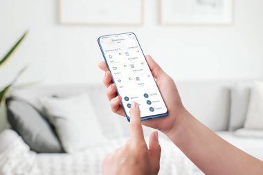 Akıllı ev kontrol uygulaması. Ev özelliklerinin otomatik denetimi ve izlenmesi kavramı. Telefon kadınların elinde.