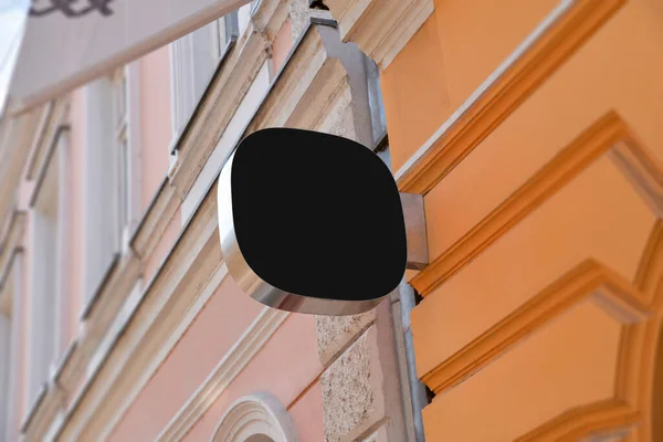 メインストリートの建物の正面にある小さな丸みを帯びた黒い看板 会社のロゴプロモーションのためのブランク — ストック写真