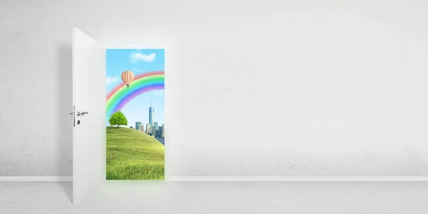 Door to a better world. The concept of a portal into virtual reality, metaverse. A smart city in the background with a rainbow, balloon and preserved nature. Copy space beside on white wall