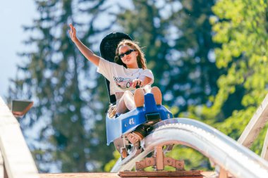 Girl is going across the bridge on a mountain roller coaster with outstretched arm