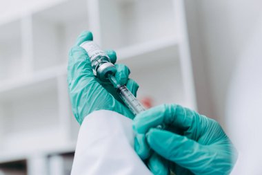 Hand of scientist or doctor holding COVID-19 vaccine bottle and syringe, prepare to be injected into people.