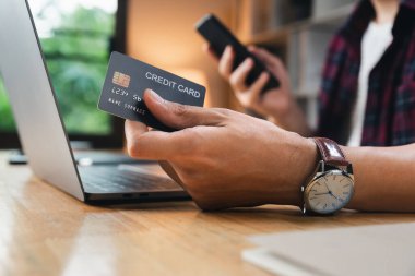 Ödeme ve alışveriş yapan genç adam kredi kartı, online iş ve ev alışverişi konseptiyle.