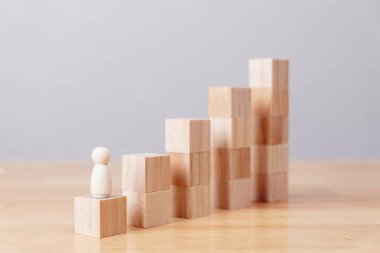 Wooden of businessman figure climbing growth chart on wood table, business and leadership concept.