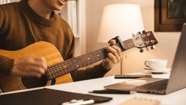 Young businessman sitting and playing guitar in office, relaxing and enjoy concept.