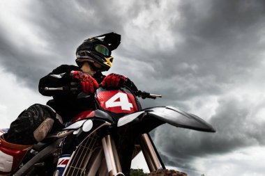 Motocross rider on his bike ready to race in dirt track, sport extreme and travel adventure concept.