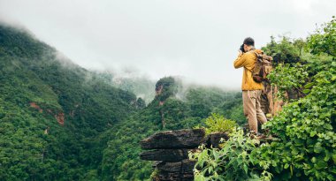 Traveler taking photo of mist in mountain at peak while hiking and camping, travel in nature.