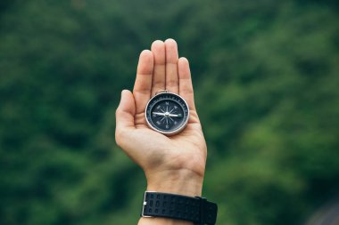 Compass in hands of traveler, At the top of peak of mountain. Sport and travel concept
