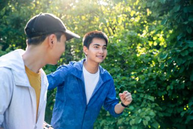 Two young handsome running on a road with green grass and trees flanking it in summer. Exercise for good health.