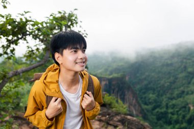 Young man going on a nature trip with backpack behind is sea of fog  and mountains. admiring nature, relaxing.