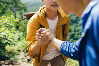 Two friend hiking with Backpack, His hand grabbed the friend in front of him as he walked up the hill.l, unity in the group.