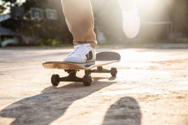 Foot of teenager playing skateboard on cement ground, extreme sport and outdoor activity.