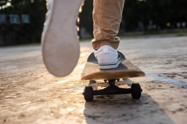 Foot of teenager playing skateboard on cement ground, extreme sport and outdoor activity.