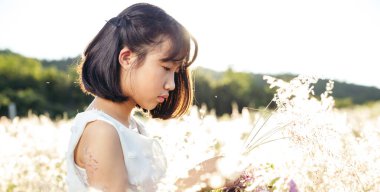 Asian girl in white dress in field at sunset, outdoors enjoying nature concept.
