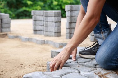 Profesyonel kaldırım işçisinin eli yol, işçilik ve endüstri konsepti için katman katman döşemektedir..