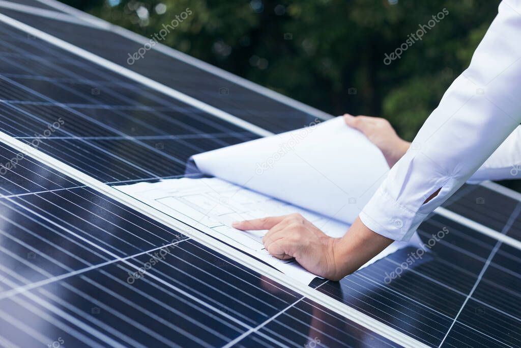 Engineer open blueprint of solar farm project on solar cells panel, summary report, technology and green ecology energy system concept.