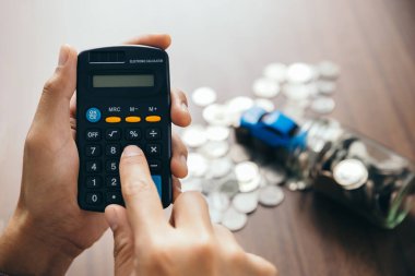 Genç adam araba, sigorta, satış, kredi, araba satın alma ve finans kavramını hesaplamak için hesap makinesi kullanıyor..