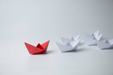 Liderlik ve takım çalışması kavramı, beyazlar arasında öncülük eden kırmızı kağıt gemi.