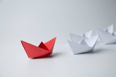 Liderlik ve takım çalışması kavramı, beyazlar arasında öncülük eden kırmızı kağıt gemi.