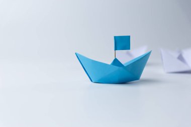 Liderlik ve takım çalışması, mavi lider kağıt gemi beyaz arka planda arka beyazı yönetiyor..