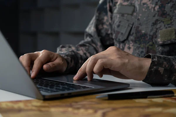 Surveillance and control of opposing information concept, Soldier in camouflage uniform working on laptop for Information Operation.