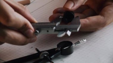 Mühendisin elleri siyah vidayı ölçmek için vernier kalibre kullanıyor.