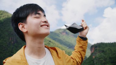 Genç turist, gaz ve kirliliğin olmadığı bir dağ zirvesinde temiz hava almak için maskesini çıkarıyor..