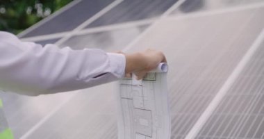Engineer open blueprint of solar farm project on solar cells panel summary report, technology and green ecology energy system concept.