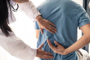Fizyoterapist, klinikte egzersiz yaptıktan sonra erkek hastaya sırt ağrısı tedavisi uyguluyor..