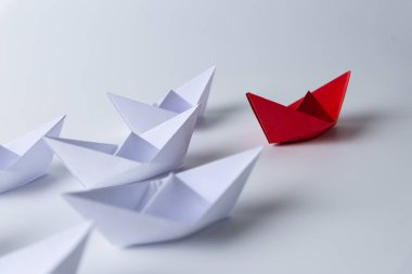 Liderlik ve takım çalışması kavramı, beyazlar arasında öncülük eden kırmızı kağıt gemi.