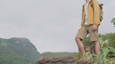 Gezgin bir uçurumun kenarına tırmanıyor ve dağa bakıyor.