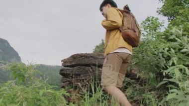 Gezgin bir uçurumun kenarına tırmanıyor ve dağa bakıyor.