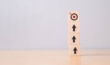 Wooden cube with target and arrow icon on table. Goals business success concept.