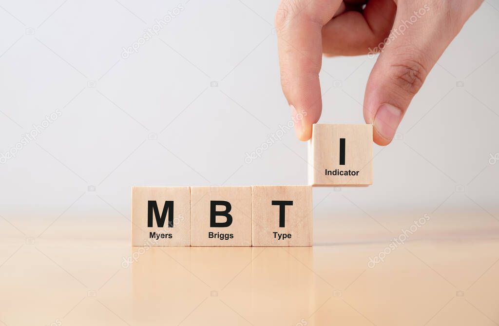 Psychological and personality test concept, Hand puts wooden cubes with MBTI, Myers-Briggs Type Indicator on table.