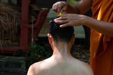 Asian man shaving his head by elder monk before ordain ceremony, Study the Dharma according to the teachings of the Buddha.
