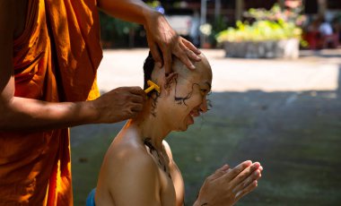 Asian man shaving his head by elder monk before ordain ceremony, Study the Dharma according to the teachings of the Buddha.